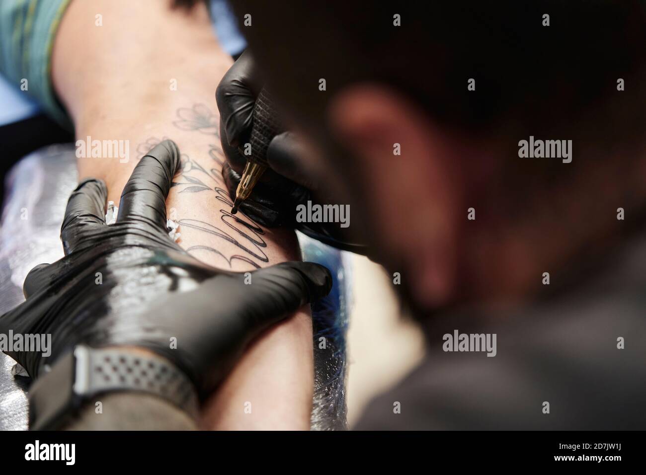 Gros plan sur le tatouage d'un artiste masculin sur la main du client en studio Banque D'Images