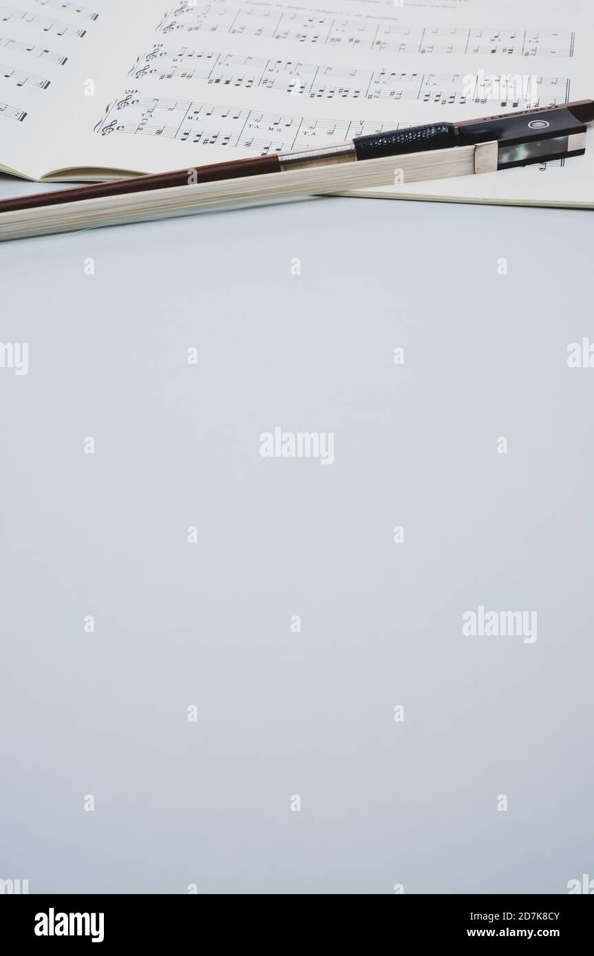 Gros plan d'un arc de violon avec partitions sur le surface grise - espace pour le texte Banque D'Images