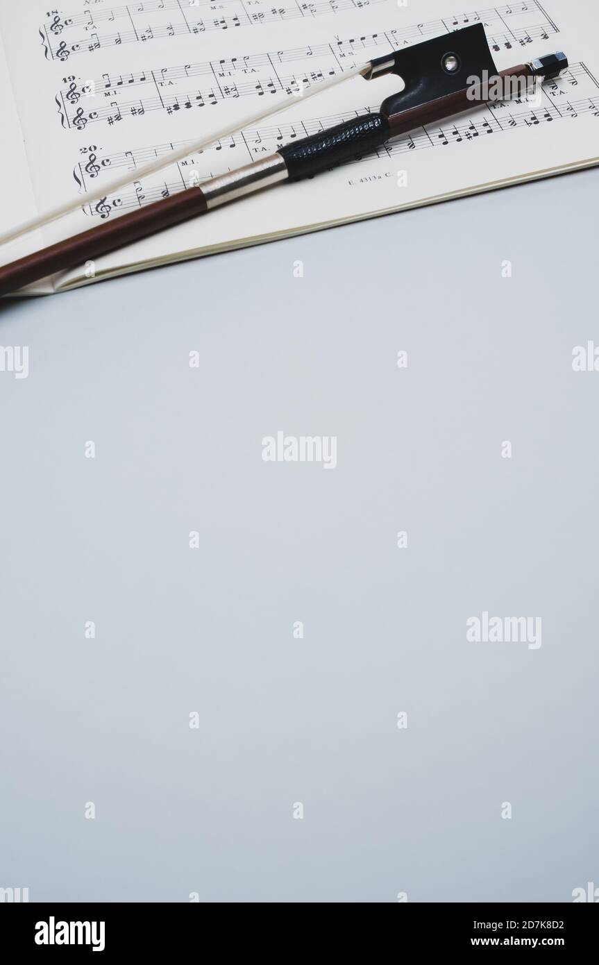 Gros plan d'un arc de violon avec partitions sur le surface grise - espace pour le texte Banque D'Images