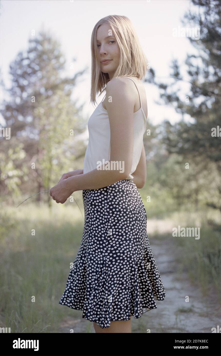 Femme blonde en jupe debout près du sentier dans la forêt printanière Photo  Stock - Alamy