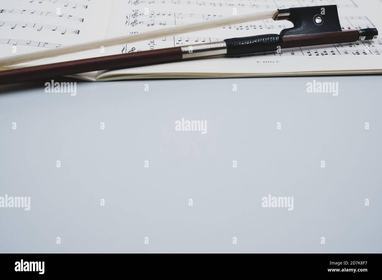 Gros plan d'un arc de violon avec partitions sur le surface grise - espace pour le texte Banque D'Images