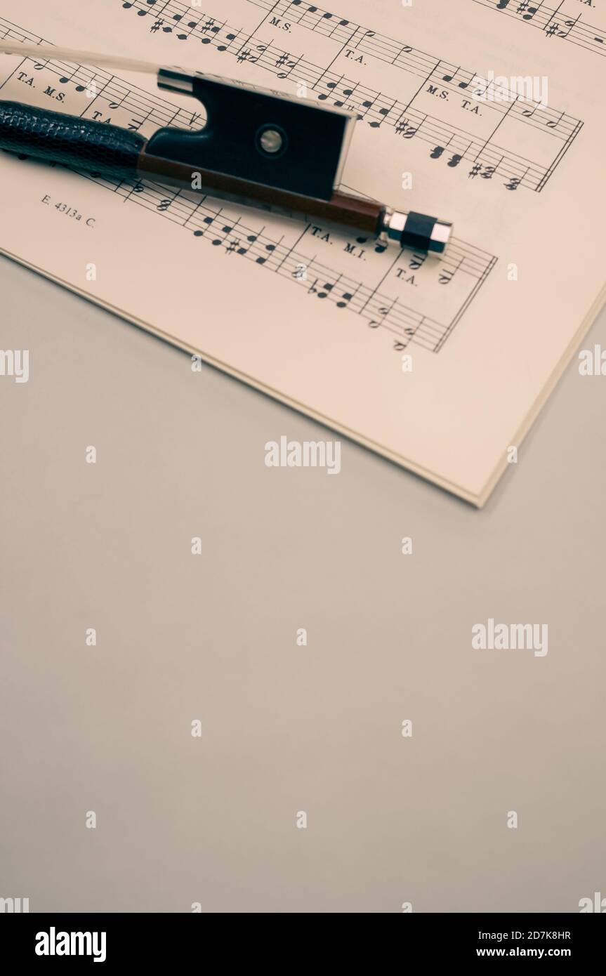 Gros plan d'un arc de violon avec partitions sur le surface grise - espace pour le texte Banque D'Images