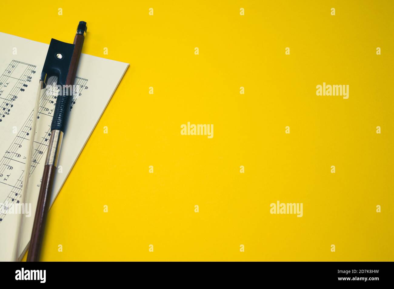 Gros plan d'un arc de violon avec partitions sur le surface jaune - espace pour le texte Banque D'Images