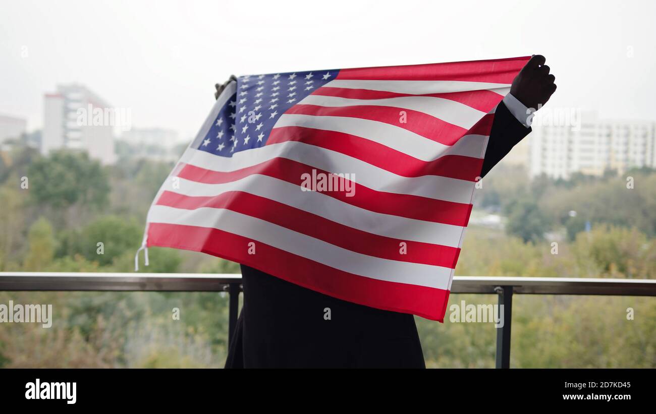 L'Afro-américain relève le drapeau national américain sur le balcon. Photo de haute qualité Banque D'Images