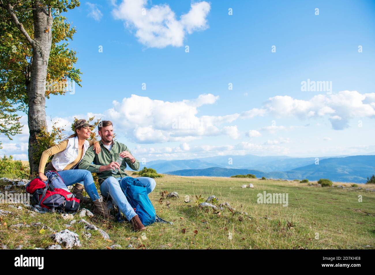 Jeune couple de l'eau potable et de se reposer sur les rochers pendant le voyage dans les montagnes Banque D'Images