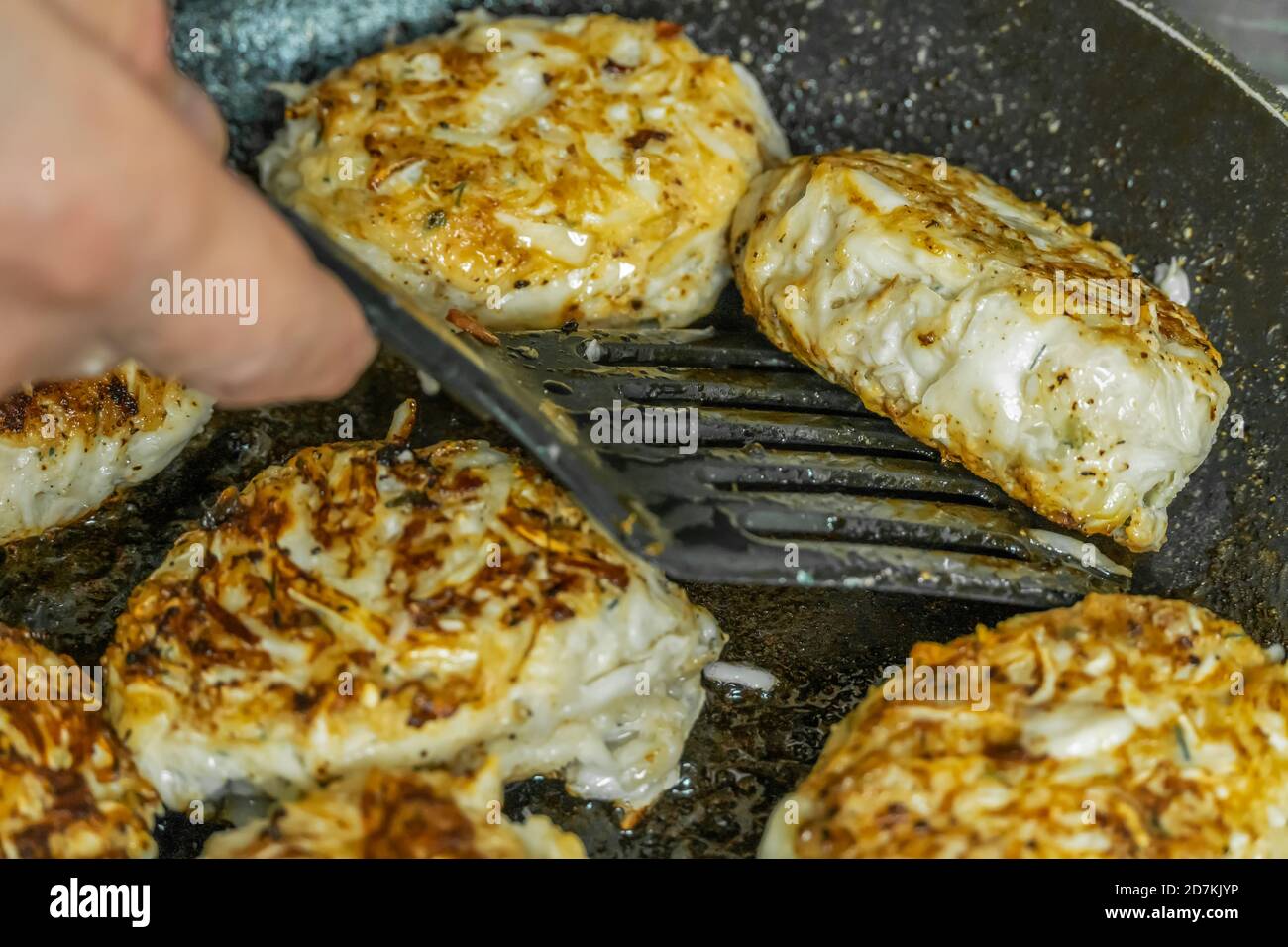 La main d'une femme retourne des côtelettes faites maison lorsqu'elle fait frire dans une poêle en gros plan dans une cuisine maison. Plats faits maison Banque D'Images