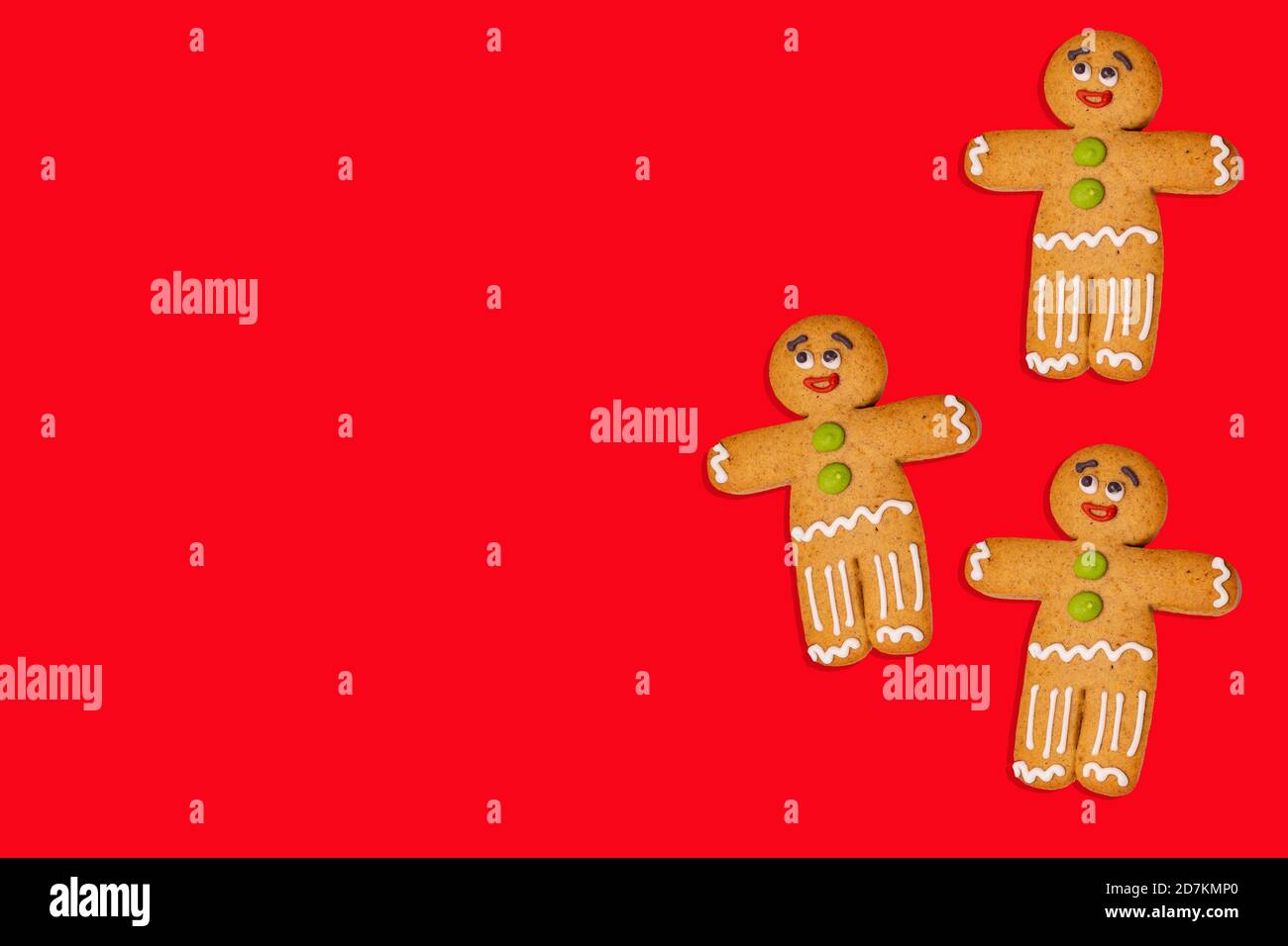 Gros plan des hommes de pain d'épice sur fond rouge. Des pains d'épice décoratifs de fête pour l'ambiance de Noël avec de l'espace pour votre texte. Concept de cookie classique Banque D'Images