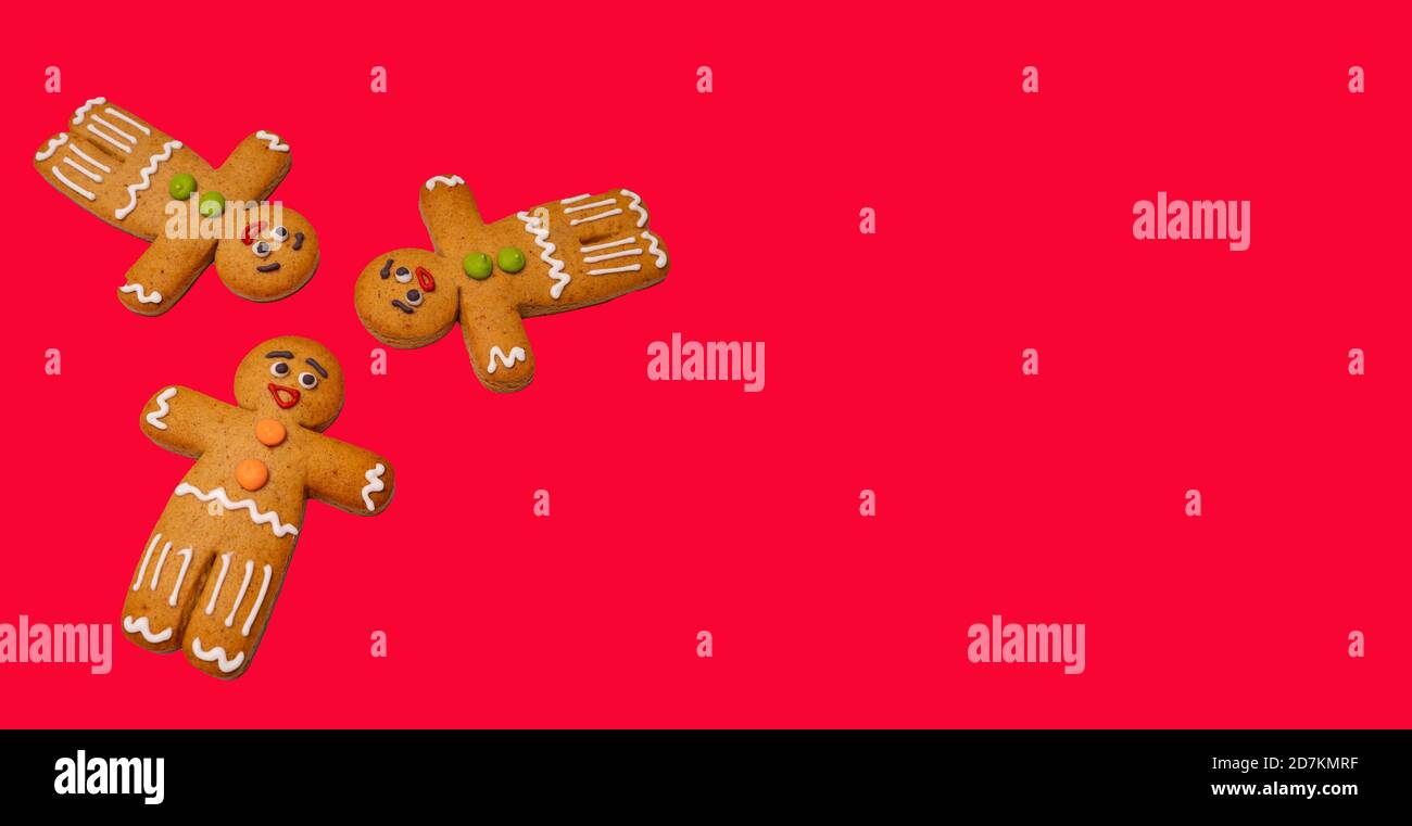 Gros plan des hommes de pain d'épice sur fond rouge. Des pains d'épice décoratifs de fête pour l'ambiance de Noël avec de l'espace pour votre texte. Concept de cookie classique Banque D'Images