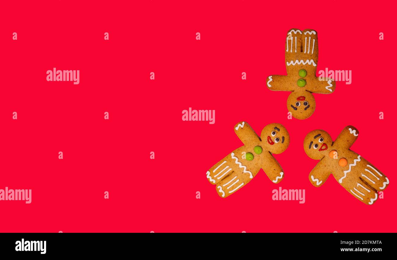 Gros plan des hommes de pain d'épice sur fond rouge. Des pains d'épice décoratifs de fête pour l'ambiance de Noël avec de l'espace pour votre texte. Concept de cookie classique Banque D'Images