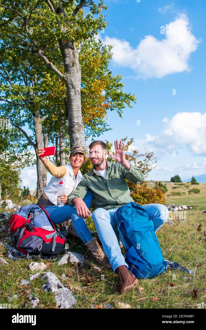 Un jeune couple joyeux qui prend un selfie en plein air pendant le voyage dans les montagnes Banque D'Images
