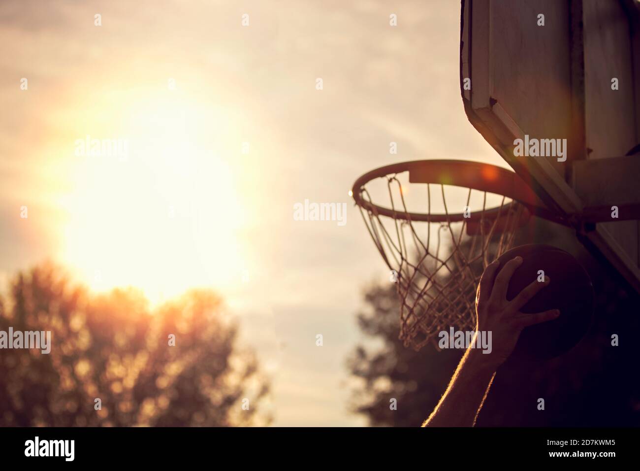 Jeune homme de saut et de faire un fantastique jeu slam dunk streetball, le basket-ball. Authentique en milieu urbain. Banque D'Images