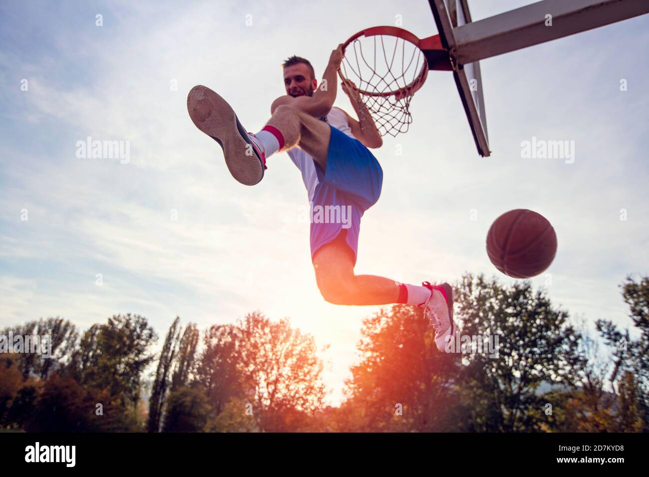 Jeune homme de saut et de faire un fantastique jeu slam dunk streetball, le basket-ball. Authentique en milieu urbain. Banque D'Images