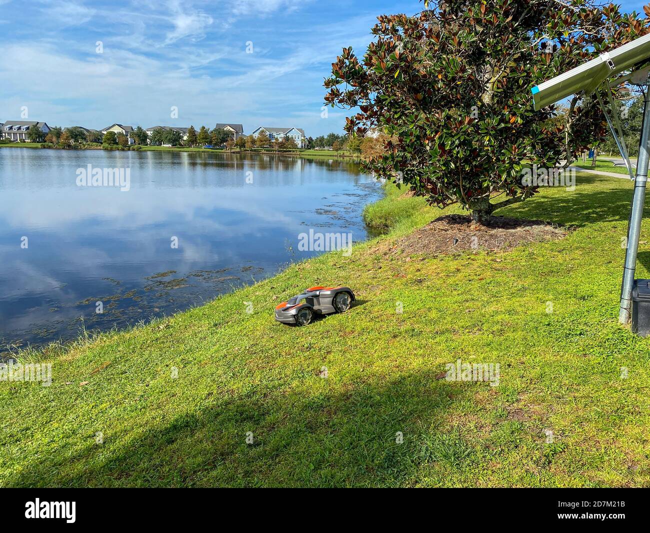 Orlando, FL./USA - 10/16/20: Une tondeuse autonome Husqvarna tondant près d'un lac dans le quartier de Laureate Park à Orlando, en Floride Banque D'Images