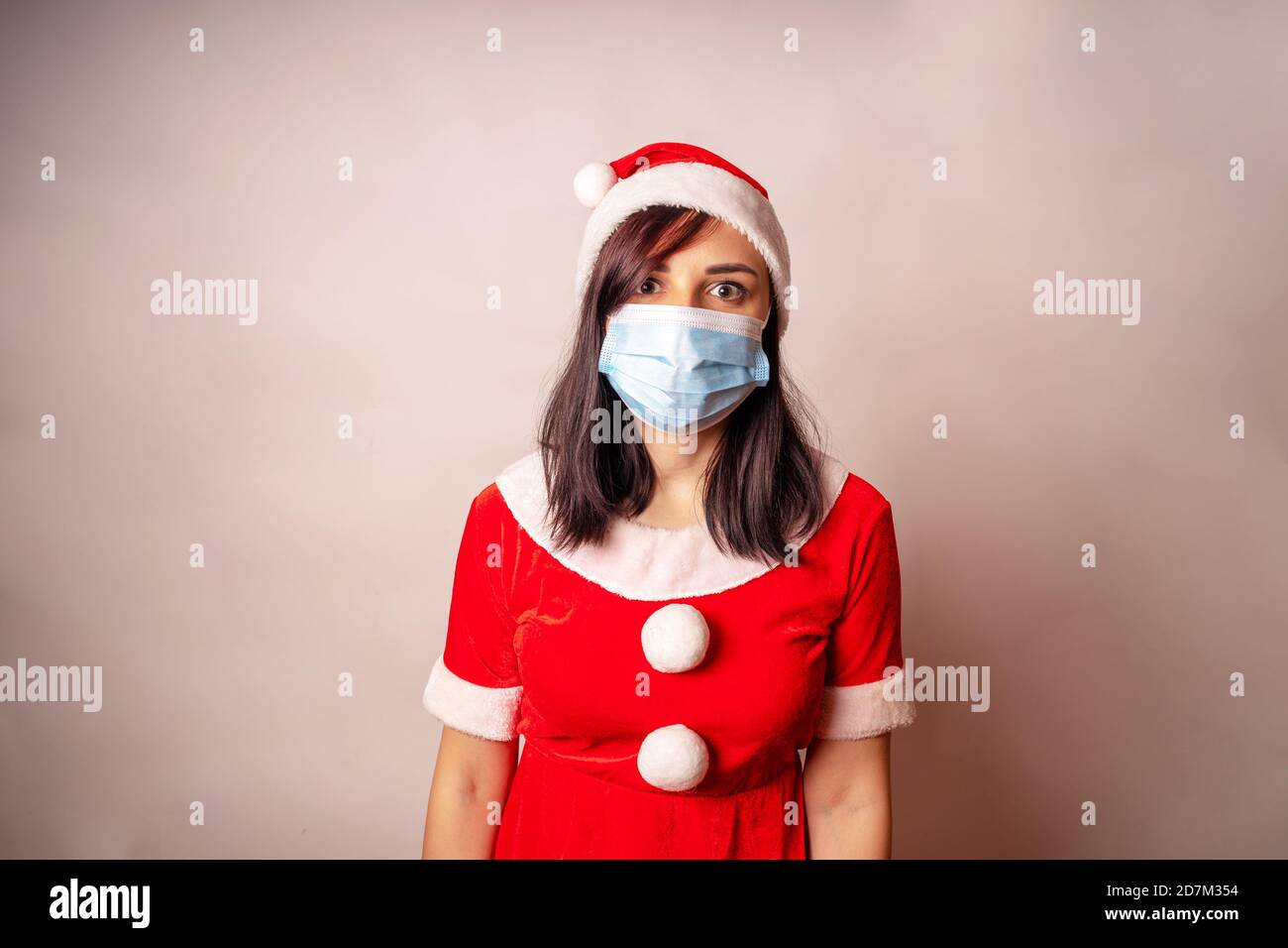 Jeune femme en masque médical et costume du Père Noël sur fond gris. Gros  plan de la femme en chapeau de Noël et masque de protection.concept de Noël  sûr Photo Stock -