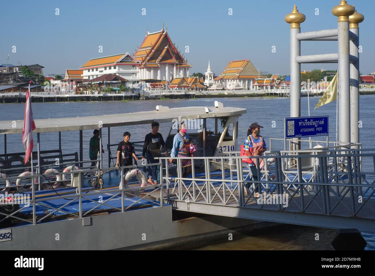 Les passagers débarquent d'un ferry traversant la rivière à l'embarcadère d'Atsadang (Yodpiman) près de la rivière Chao Phraya à Bangkok, en Thaïlande; b/g: (temple) Wat Kalayanamit Banque D'Images