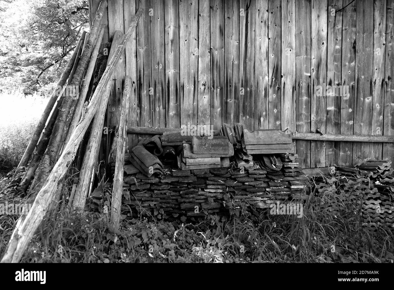 Plan en échelle de gris de planches en bois et de matériaux de toiture près d'un ancienne grange dans un champ Banque D'Images