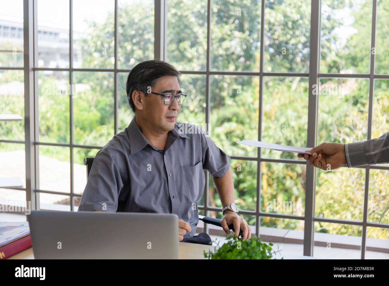 La main qui livre des documents à un homme asiatique en difficulté d'âge moyen avec les mauvaises nouvelles: Les entrepreneurs désespérés sont mis à pied, se cachent, pleurer, déçus Banque D'Images