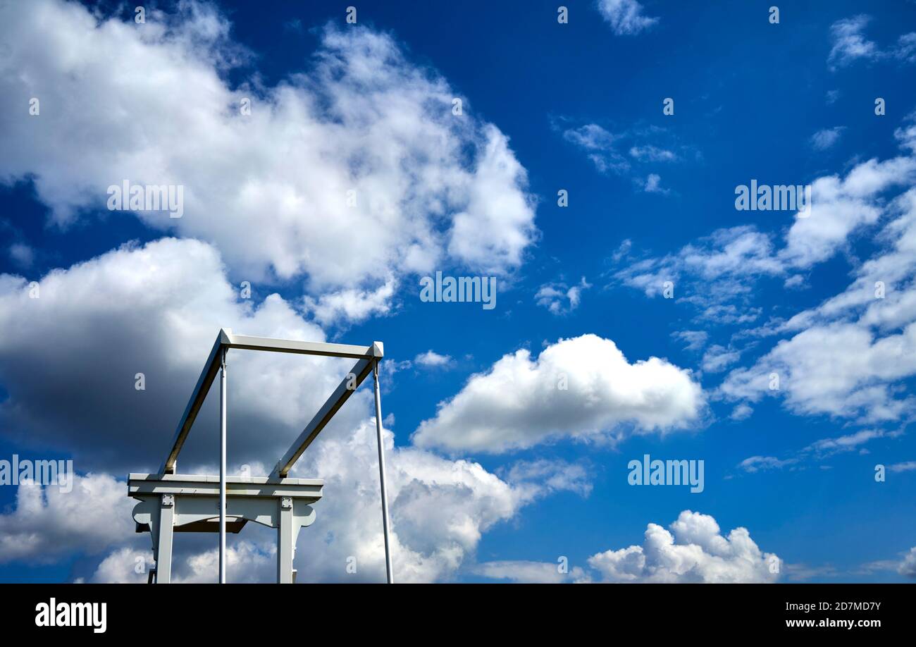 Charnière supérieure blanche des poutres de levage d'un pont-levis devant un ciel bleu avec des nuages blancs spectaculaires Banque D'Images