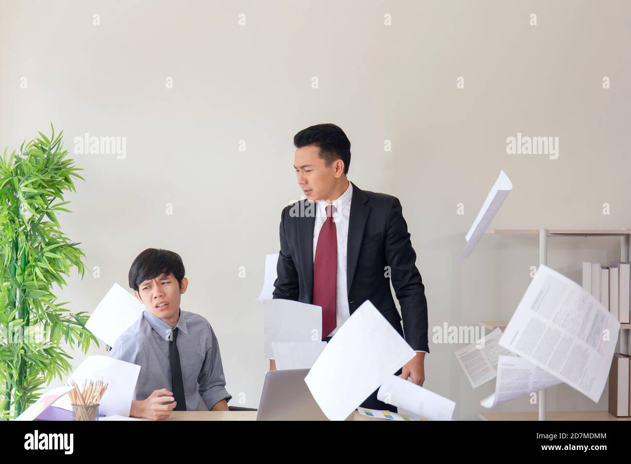 Un responsable asiatique en colère, ses employés ne peuvent pas travailler comme prévu, jetant du papier dans le bureau. Banque D'Images