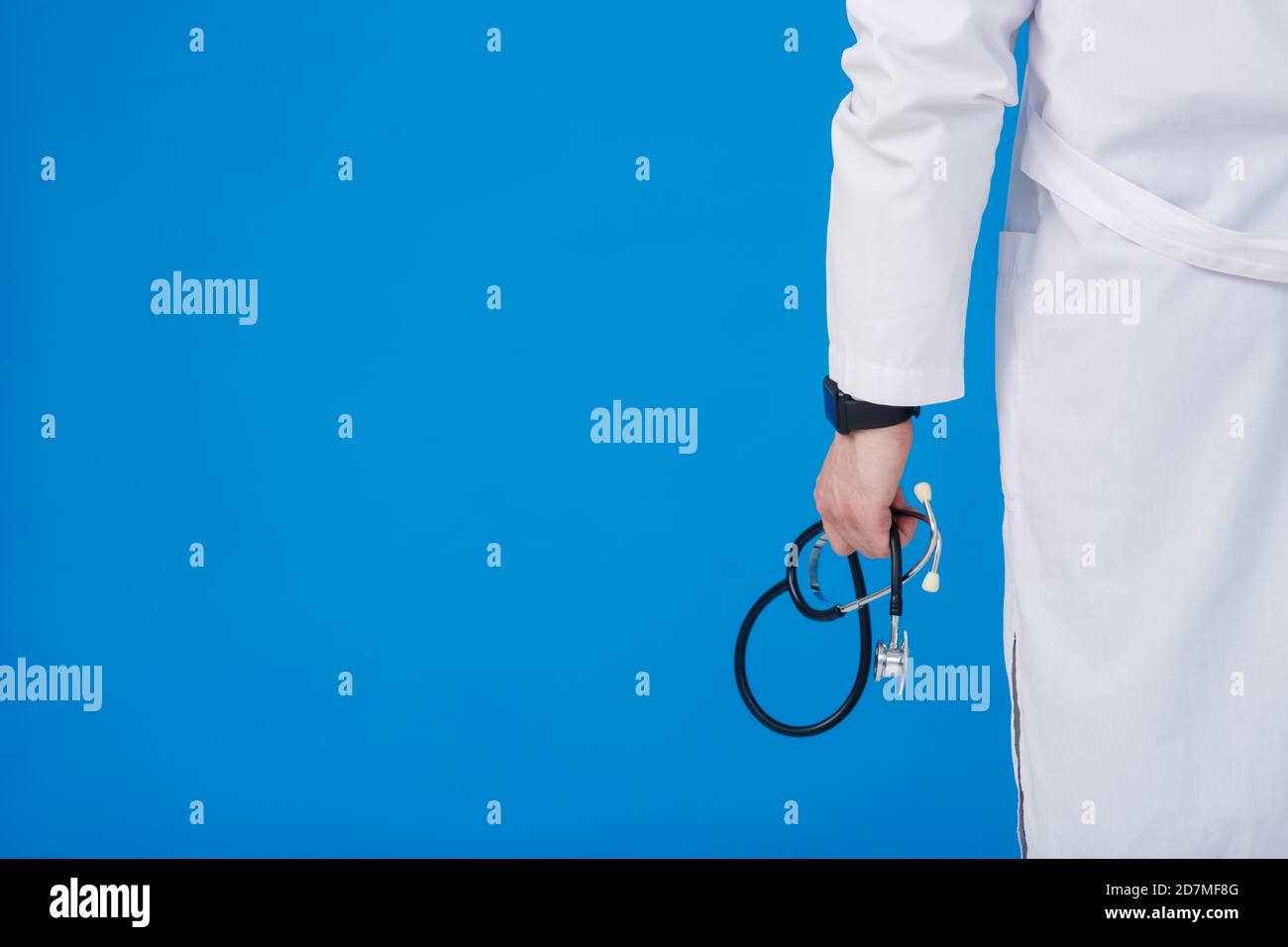 Médecin avec un stéthoscope à la main, fond bleu gros plan Banque D'Images