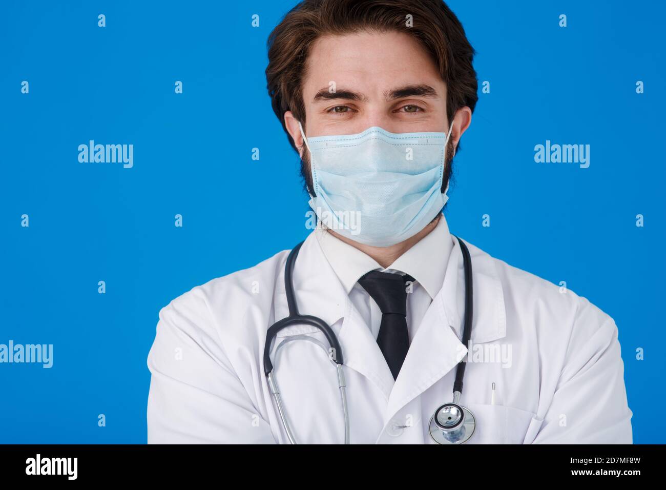 Médecin sous un manteau blanc et un masque médical, avec un endoscope autour de son cou de près - sur un fond bleu. Concept de protection contre les virus et Banque D'Images