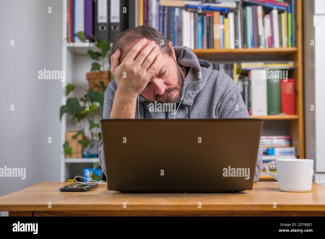 Homme frustré, travaillant en ligne depuis le bureau à domicile sur ordinateur portable derrière le bureau d'époque, fatigué et épuisé après la réunion en ligne Banque D'Images