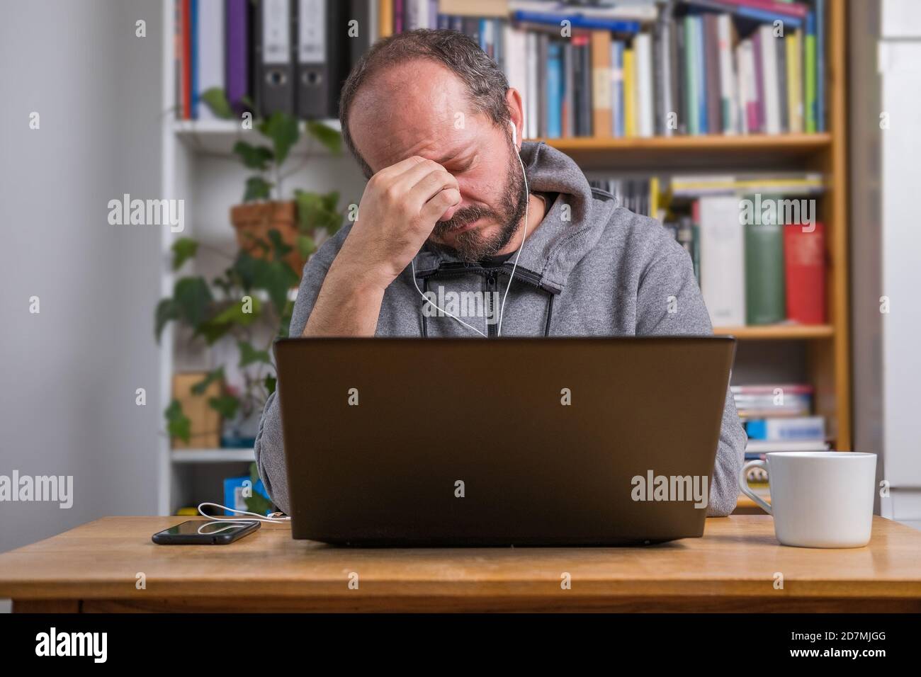 Homme frustré, travaillant en ligne depuis le bureau à domicile sur ordinateur portable derrière le bureau d'époque, fatigué et épuisé après la réunion en ligne Banque D'Images