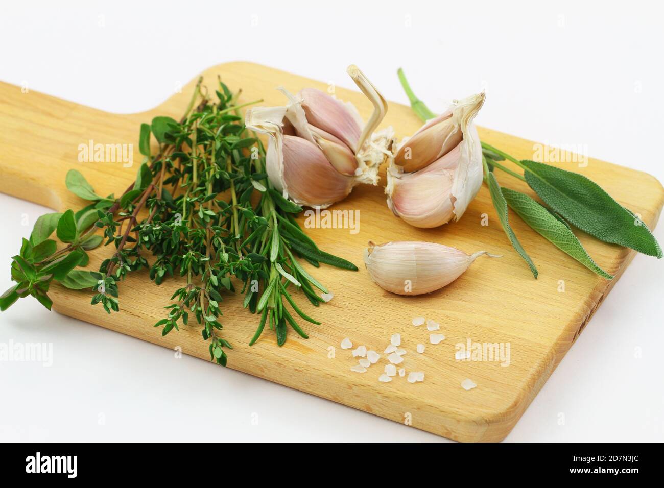 Herbes fraîches sur bois sur fond blanc (coriandre, thym, romarin, sauge) et gousses d'ail Banque D'Images