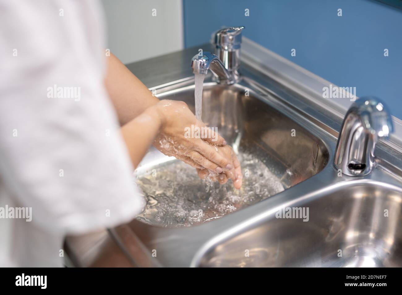 Jeune assistant ou chirurgien en uniforme blanc se lavant les mains après fonctionnement Banque D'Images