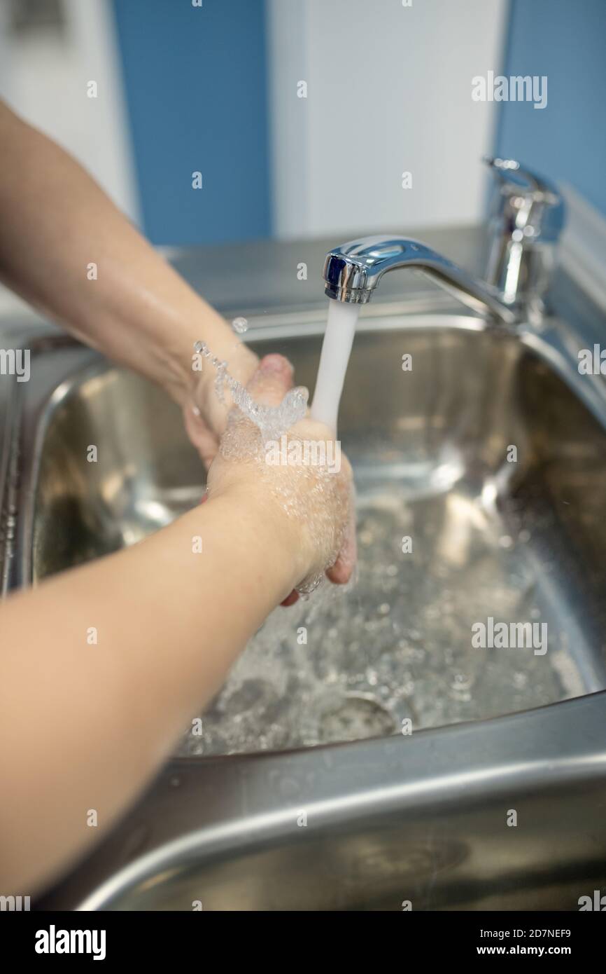 Un jeune assistant ou un chirurgien professionnel se lavant les mains sur un évier métallique Banque D'Images
