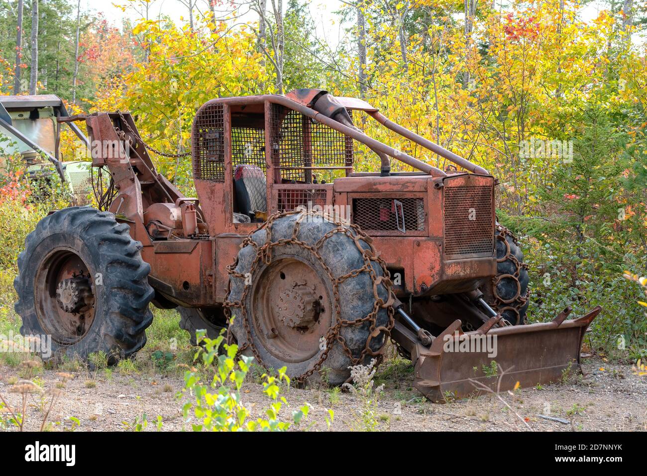Un vieux tracteur lourd, rouillé, abandonné avec une charrue à l'avant. Le tracteur est à côté d'une forêt. Chaînes sur les pneus avant. Pas de marquage d'identification. Banque D'Images
