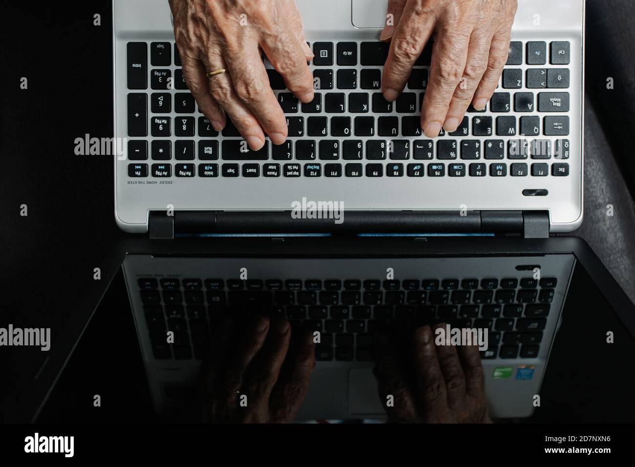 Vue de dessus de Crop anonyme travailleur à distance dactylographiant sur le clavier de l'ordinateur portable tout en étant assis à la table sur le lieu de travail. Banque D'Images