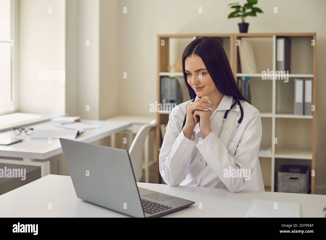 Une femme médecin est assise devant un ordinateur portable et examine les résultats d'un examen médical. Banque D'Images