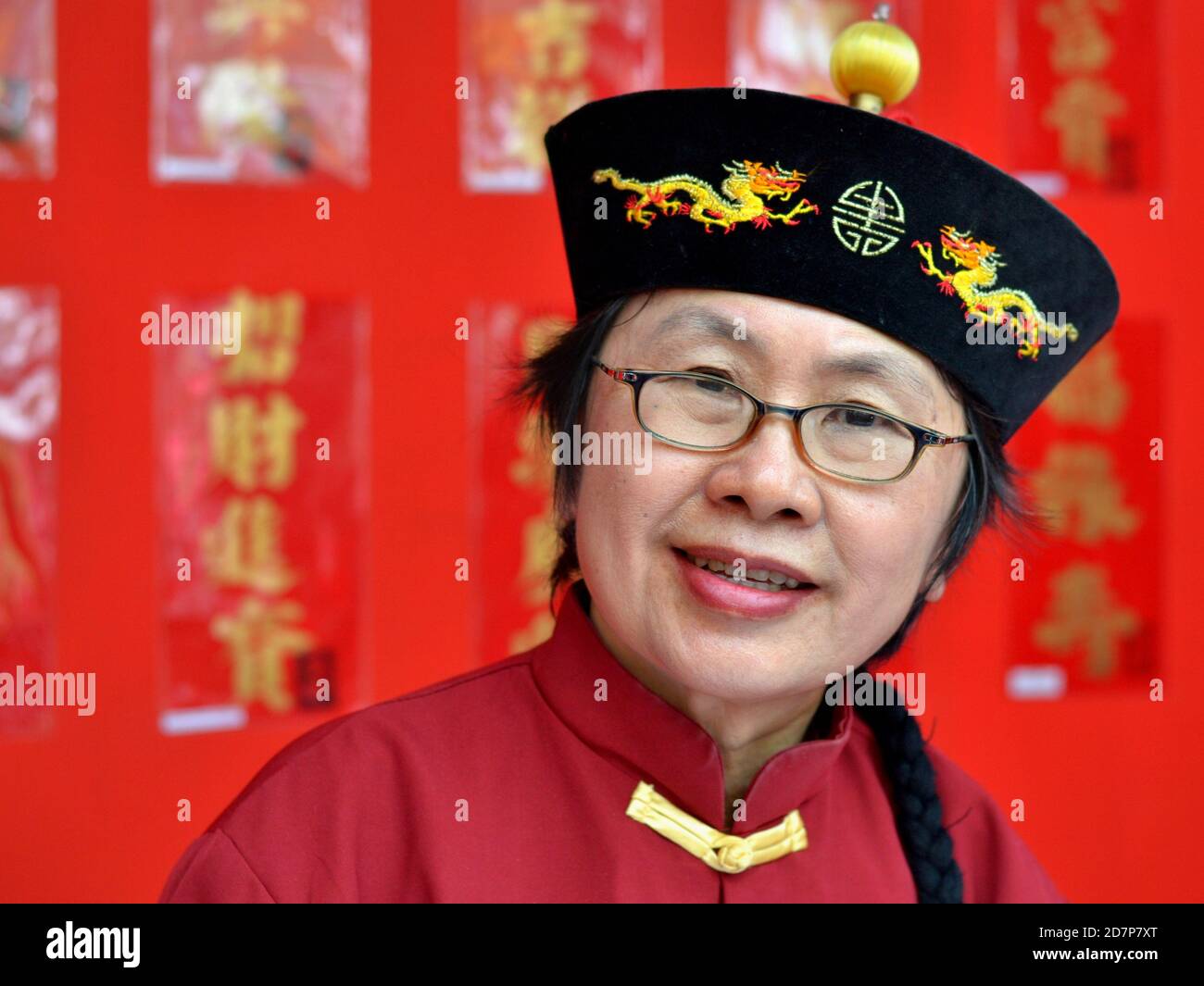 Le maître de calligraphie thaï chinois porte un chapeau officiel royal de la dynastie Qing de velours avec deux dragons et sourires pour la caméra pendant le nouvel an chinois. Banque D'Images