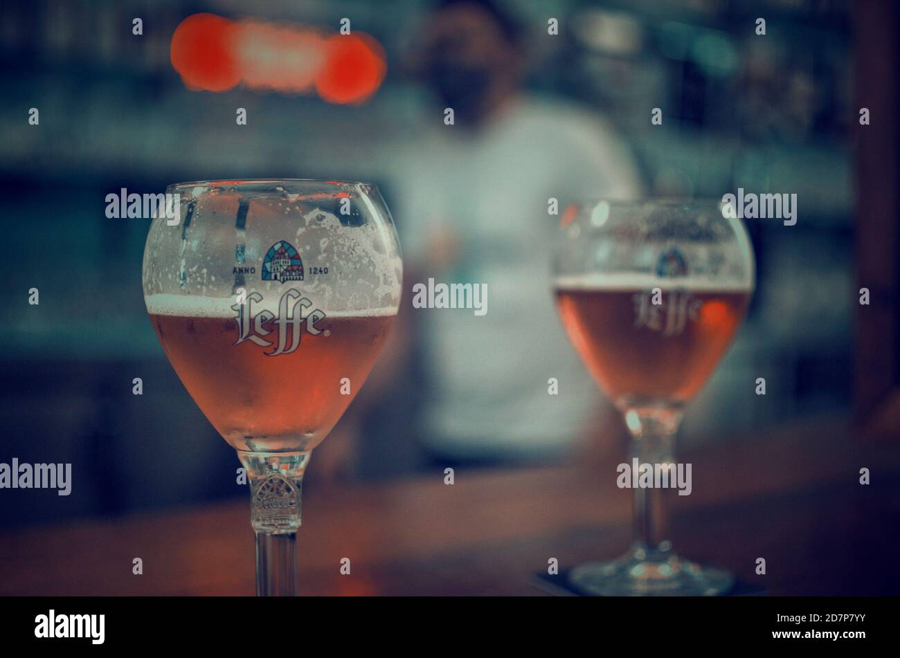 Accent sélectif sur un verre de bière. Arrière-plan flou d'un serveur portant un masque facial. Banque D'Images