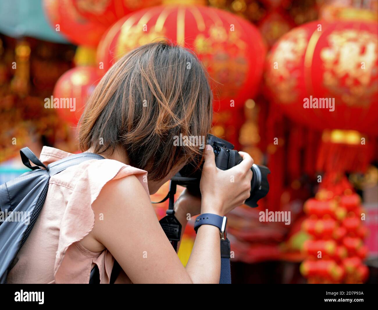 La photographe chinoise féminine prend une photo de souvenirs de bonne chance colorés et de lanternes traditionnelles en papier rouge et or au nouvel an chinois. Banque D'Images