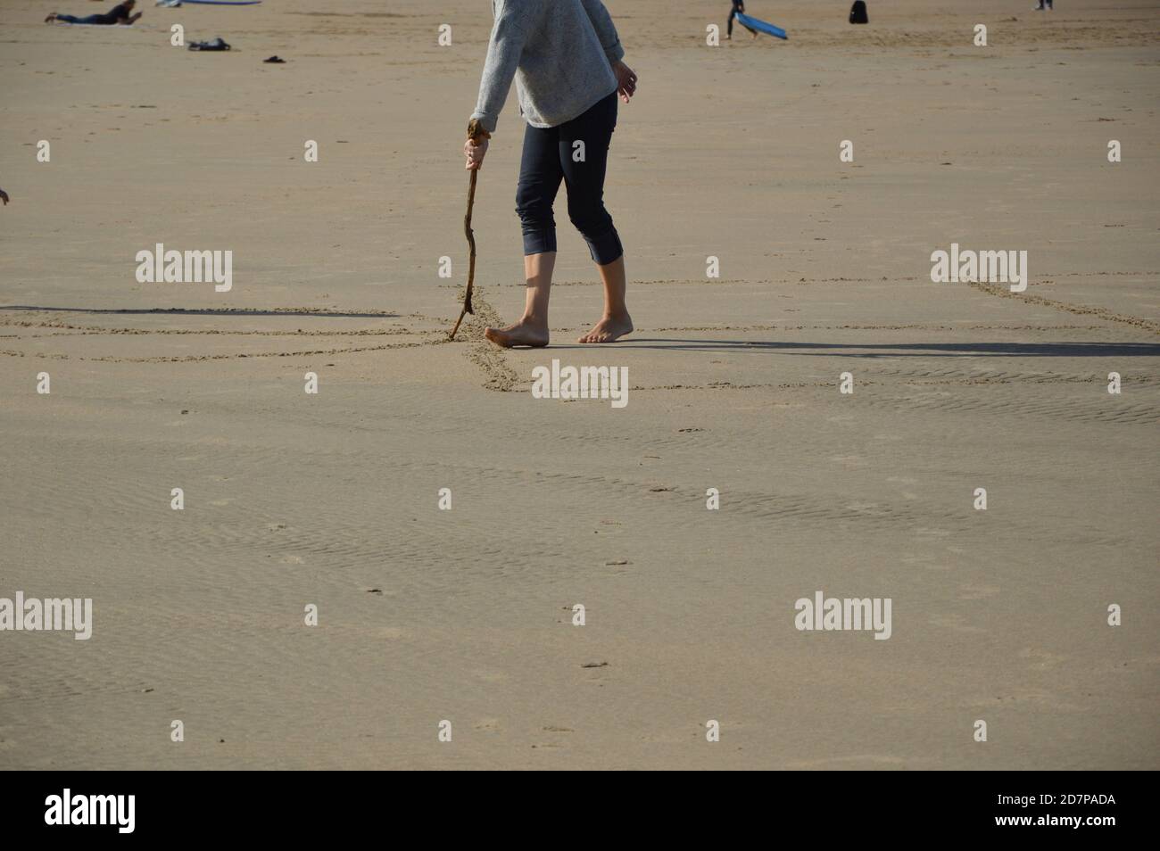 Personne avec un bâton de bois dessinant sur une plage sous la lumière du soleil Banque D'Images