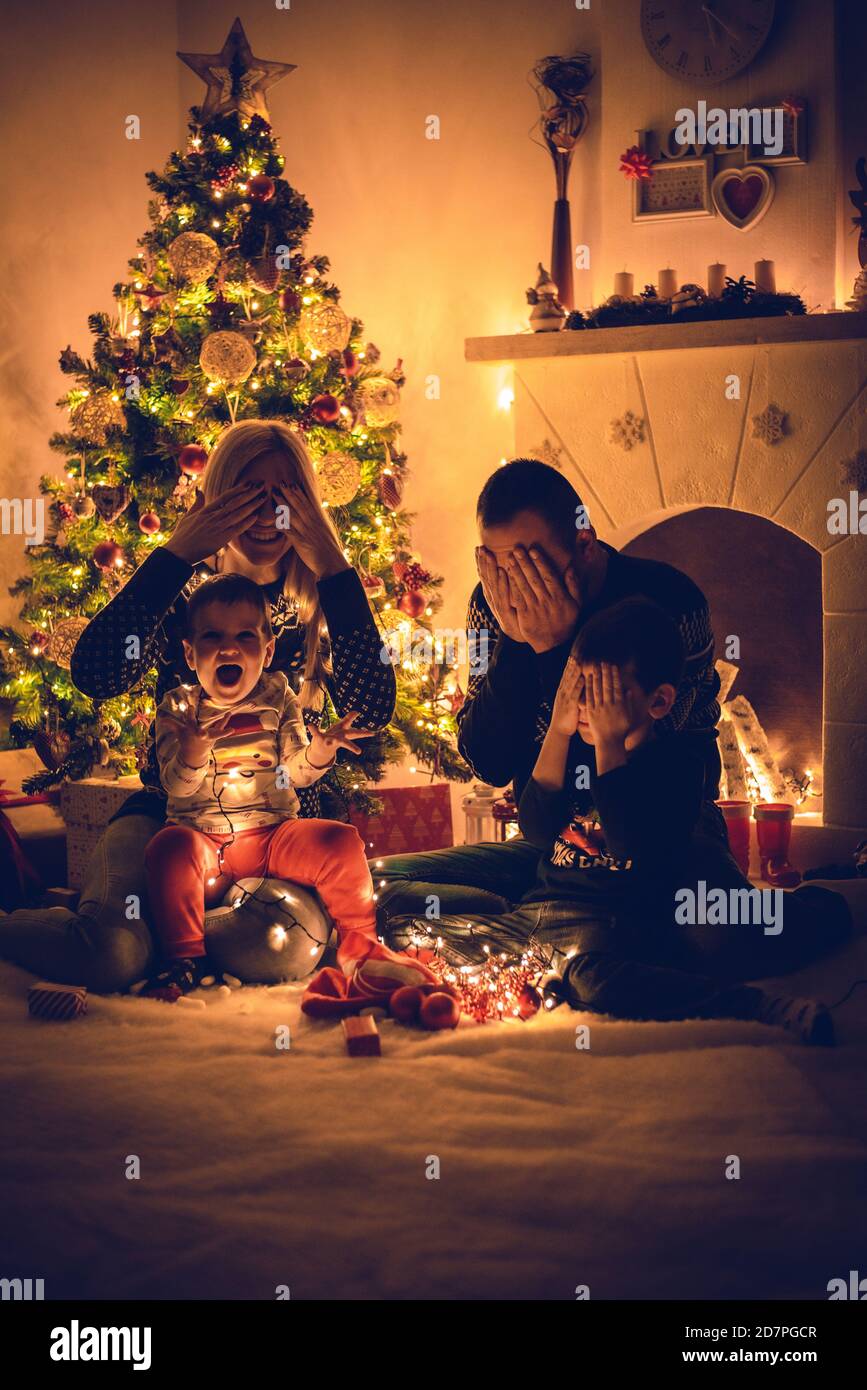 La famille invite le Père Noël et des cadeaux devant l'arbre À la veille de Noël - le plus jeune garçon a vu le Père Noël en premier Banque D'Images