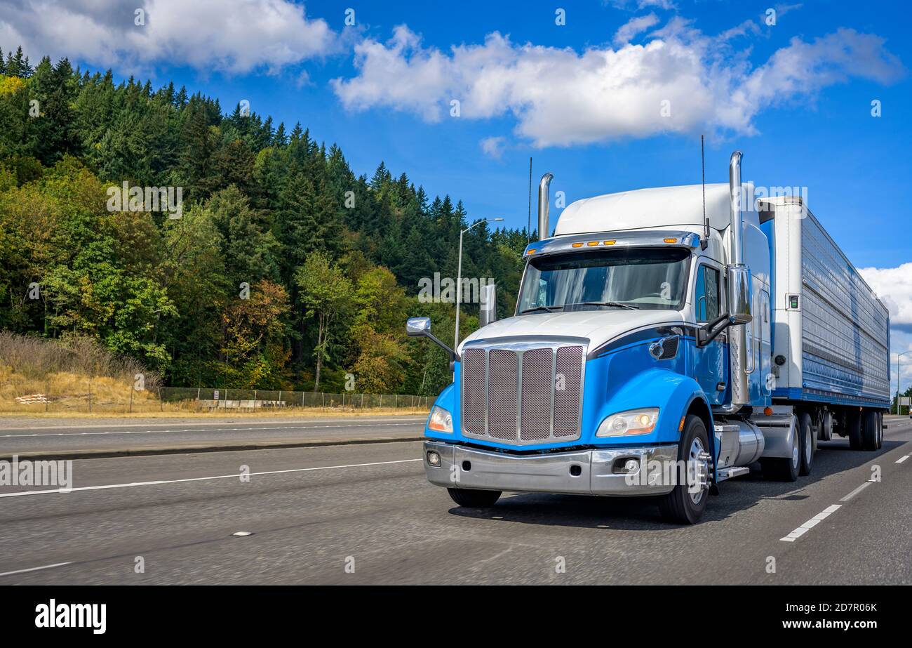 Transporteur long à capot de qualité industrielle pour gros engin de forage bleu et blanc semi-camion diesel avec réfrigérateur semi-remorque fonctionnant avec le commerce chargement sur le large Banque D'Images