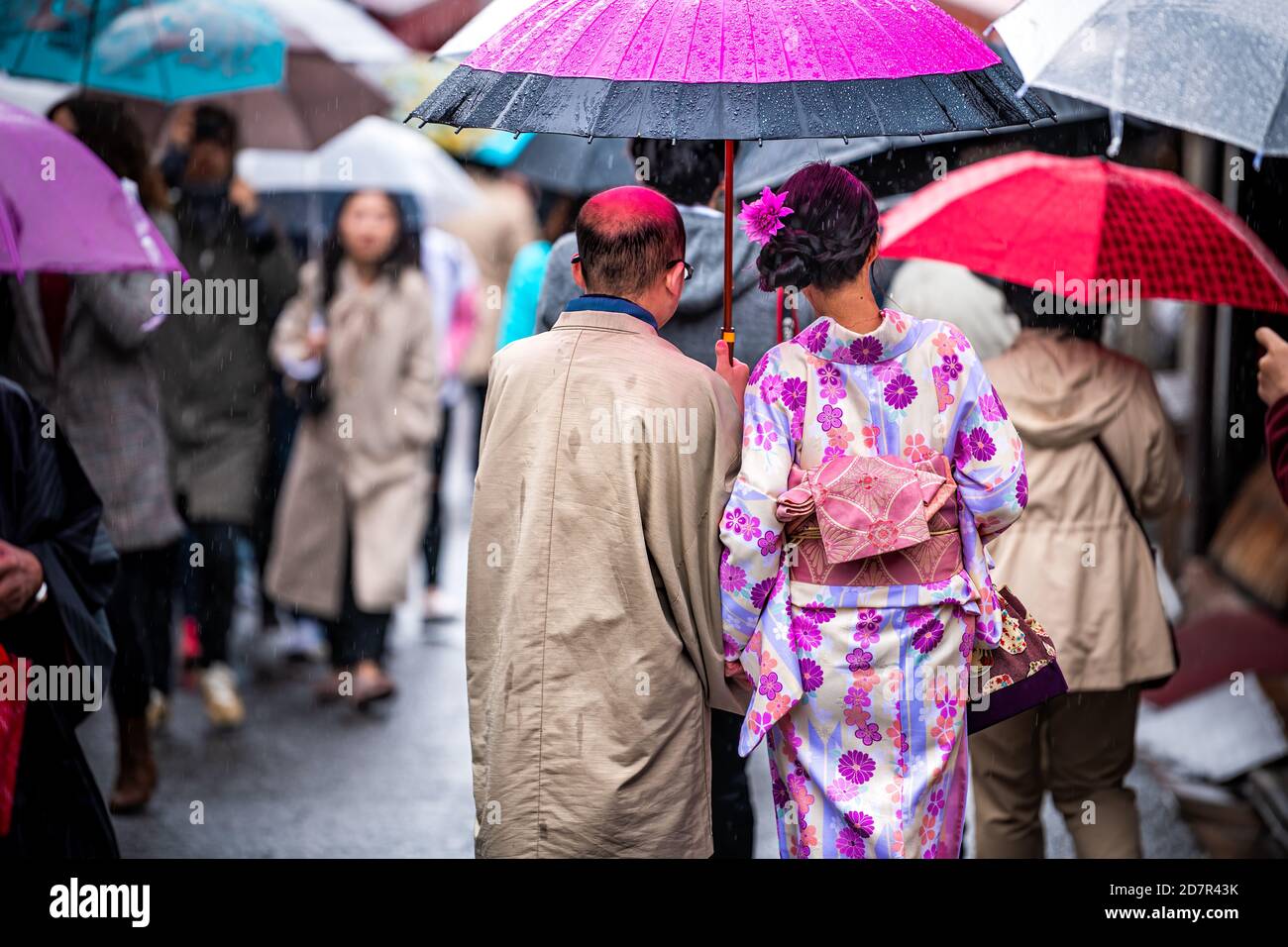 Kyoto, Japon - 10 avril 2019 : les gens de derrière de femme et d'homme portant un parapluie vêtus de costume kimono pendant la journée des pluies sur la rue ne Banque D'Images