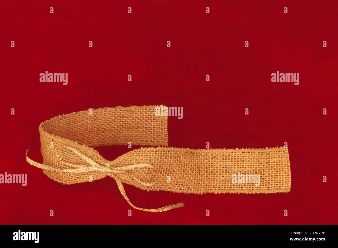 Espace de texte au-dessus du ruban de toile de jute beige doré sur fond de tissu rouge. Banque D'Images