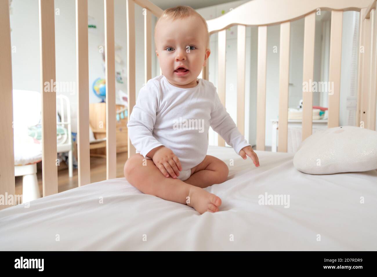 Blond Mignon Petit Bleu Eyed Bebe Dans Le Body Blanc Assis Lit En Bois Photo Stock Alamy