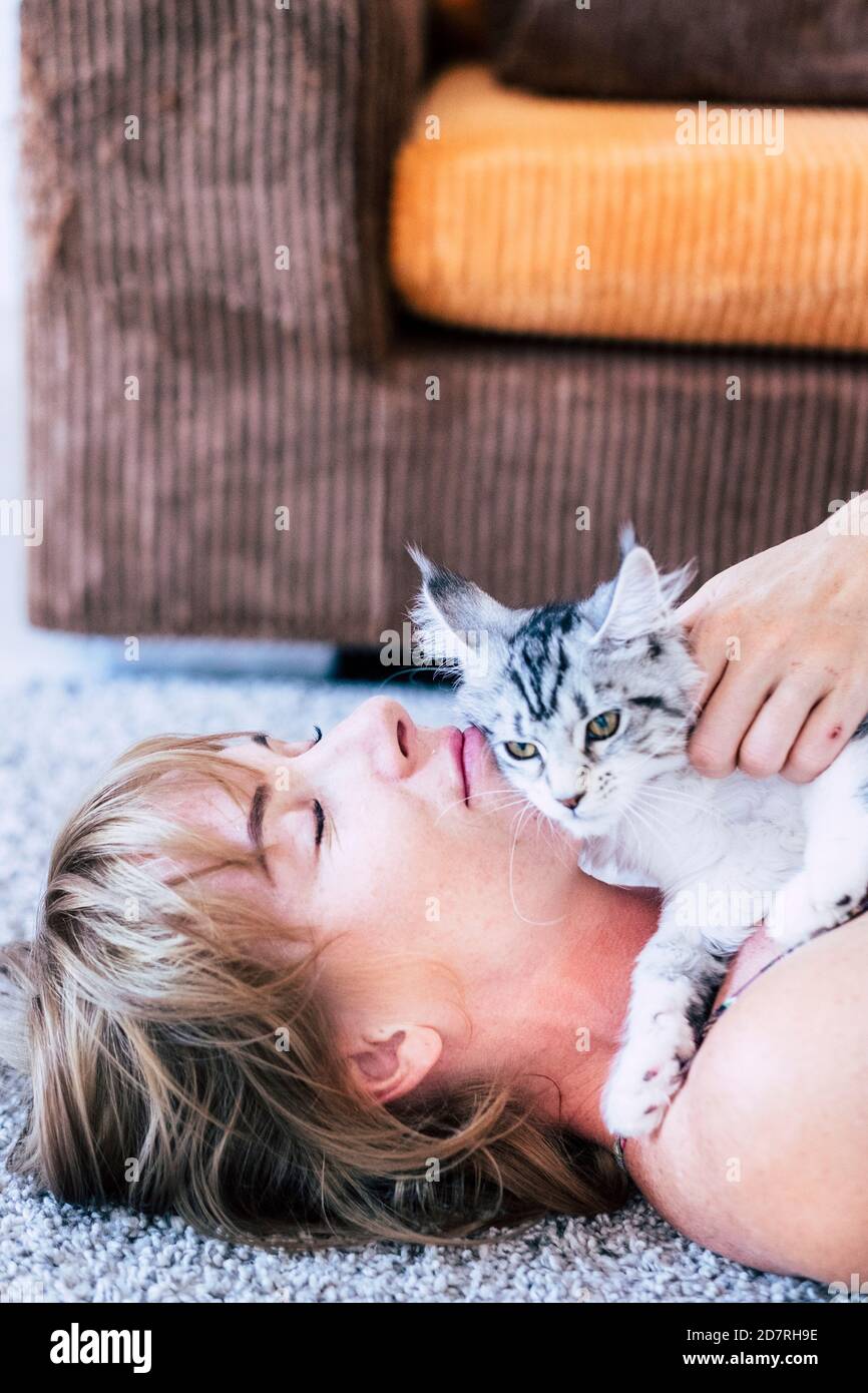 Femme avec beau portrait de chat - jeune femme de race blanche installez-vous sur le sol à la maison et détendez-vous avec son adorable félin sur elle Banque D'Images