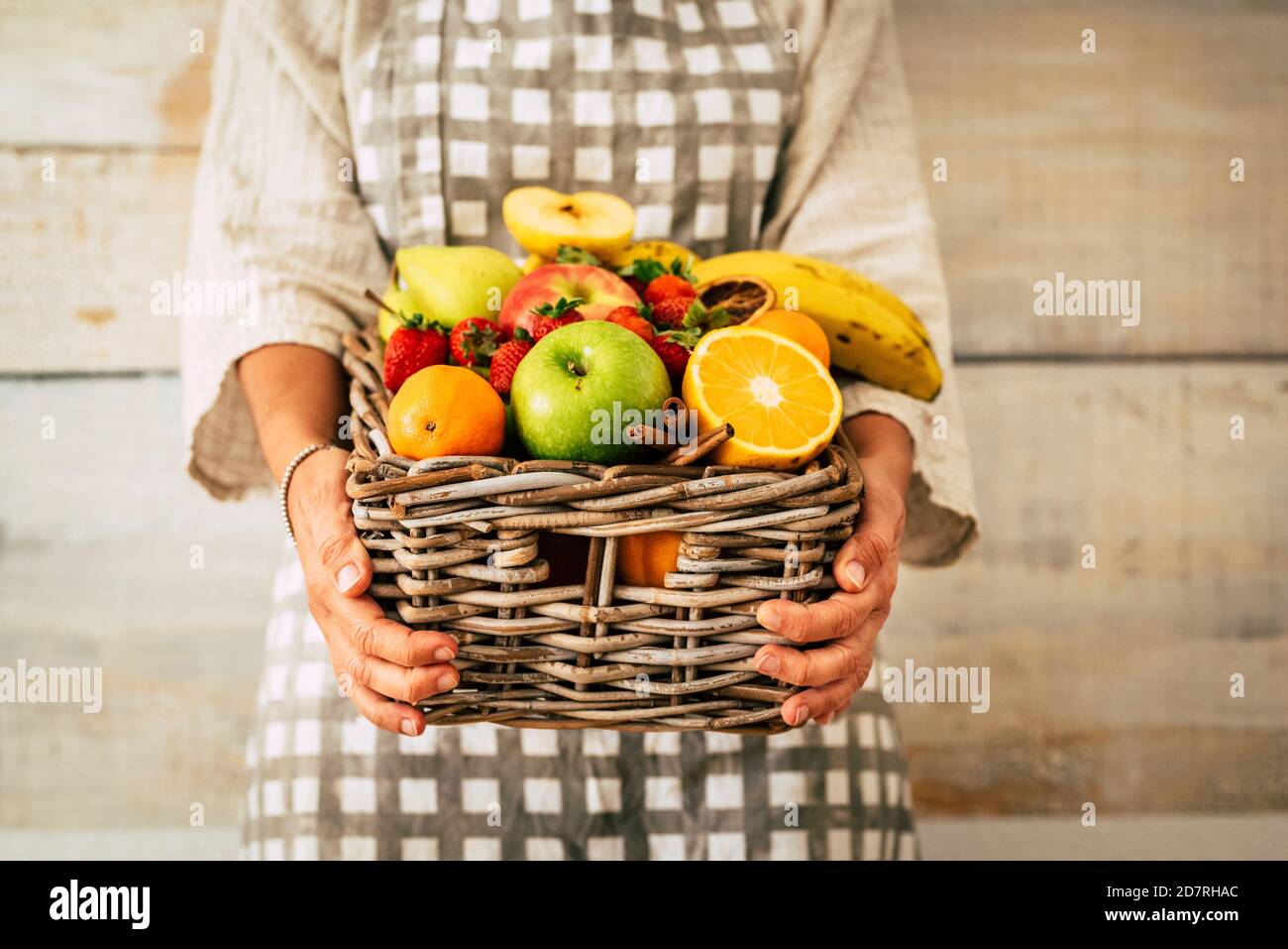 Seau de fruits frais entroué par une femme adulte avec fond de mur - concept de perte de poids et de commerce de fruits - agriculture et vie professionnelle des agriculteurs Banque D'Images