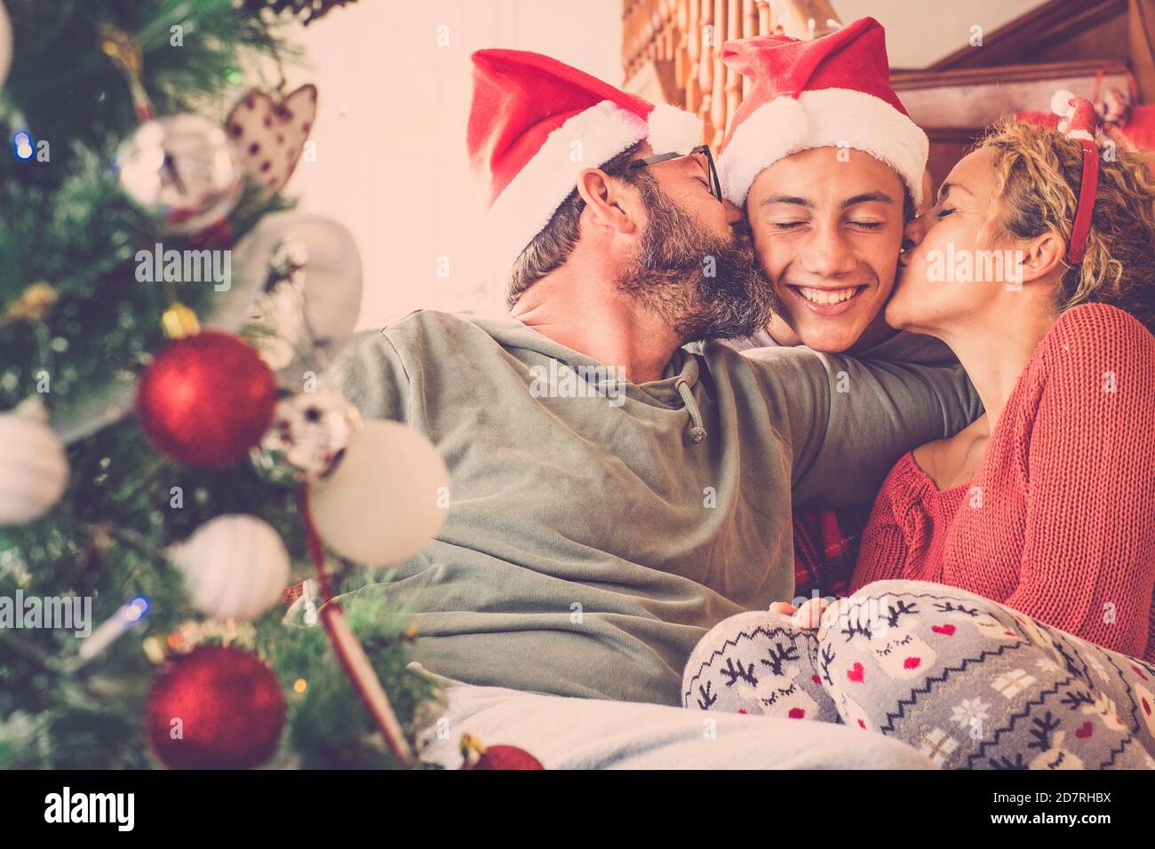 Famille heureuse dans l'amour fêtez la veille de noël avec baiser et câlin et joie - joyeux gens avec le rouge décorations d'hiver à la maison - concept de f Banque D'Images