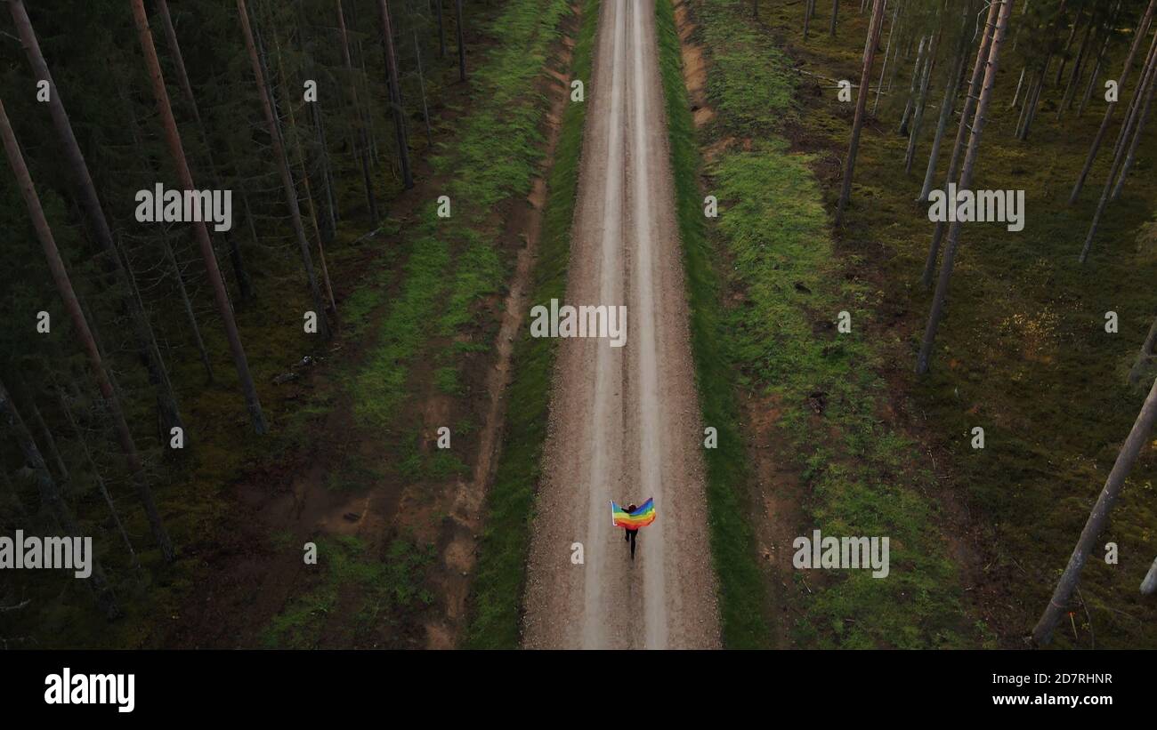 Vue aérienne d'une femme qui court avec un grand arc-en-ciel LGBT drapeau Banque D'Images