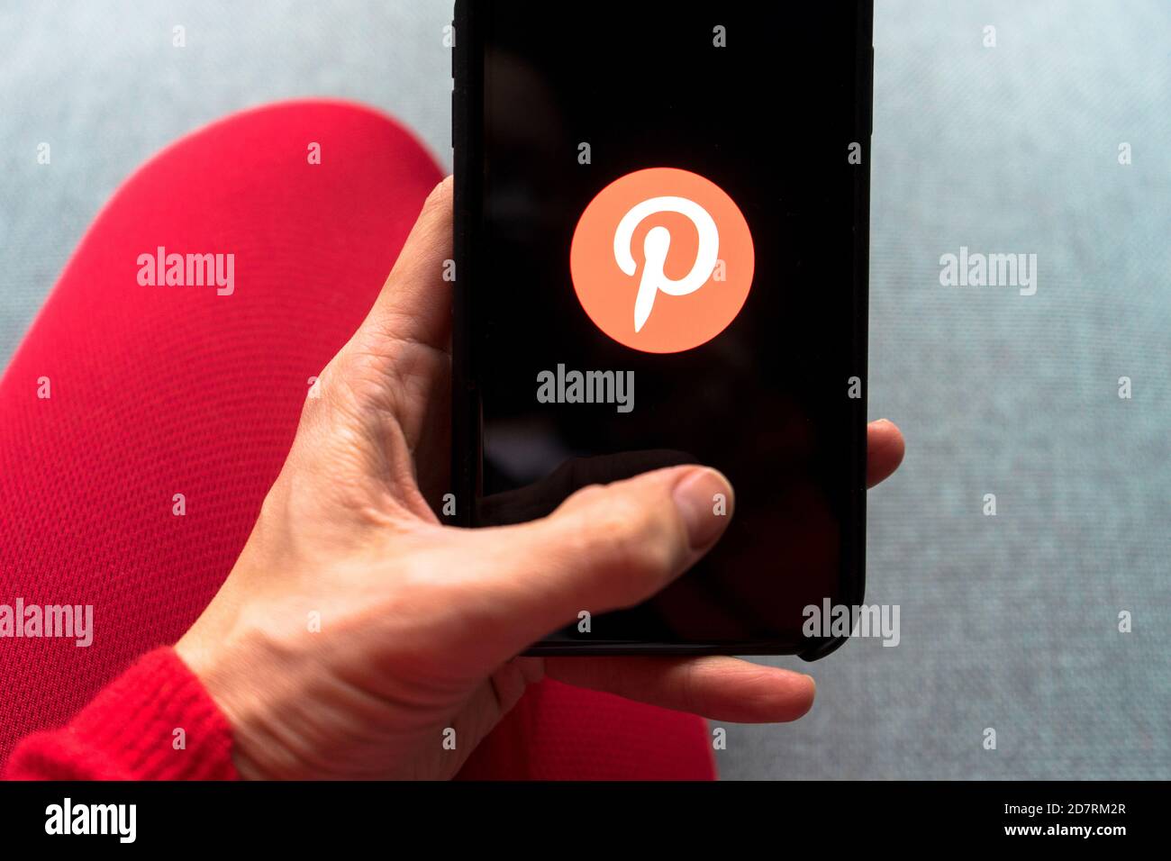 Jeune femme tenant un smartphone avec l'application Pinterest à l'écran. IPhone 11 avec un logo d'application de médias sociaux pour un contenu intéressant et exceptionnel. Banque D'Images