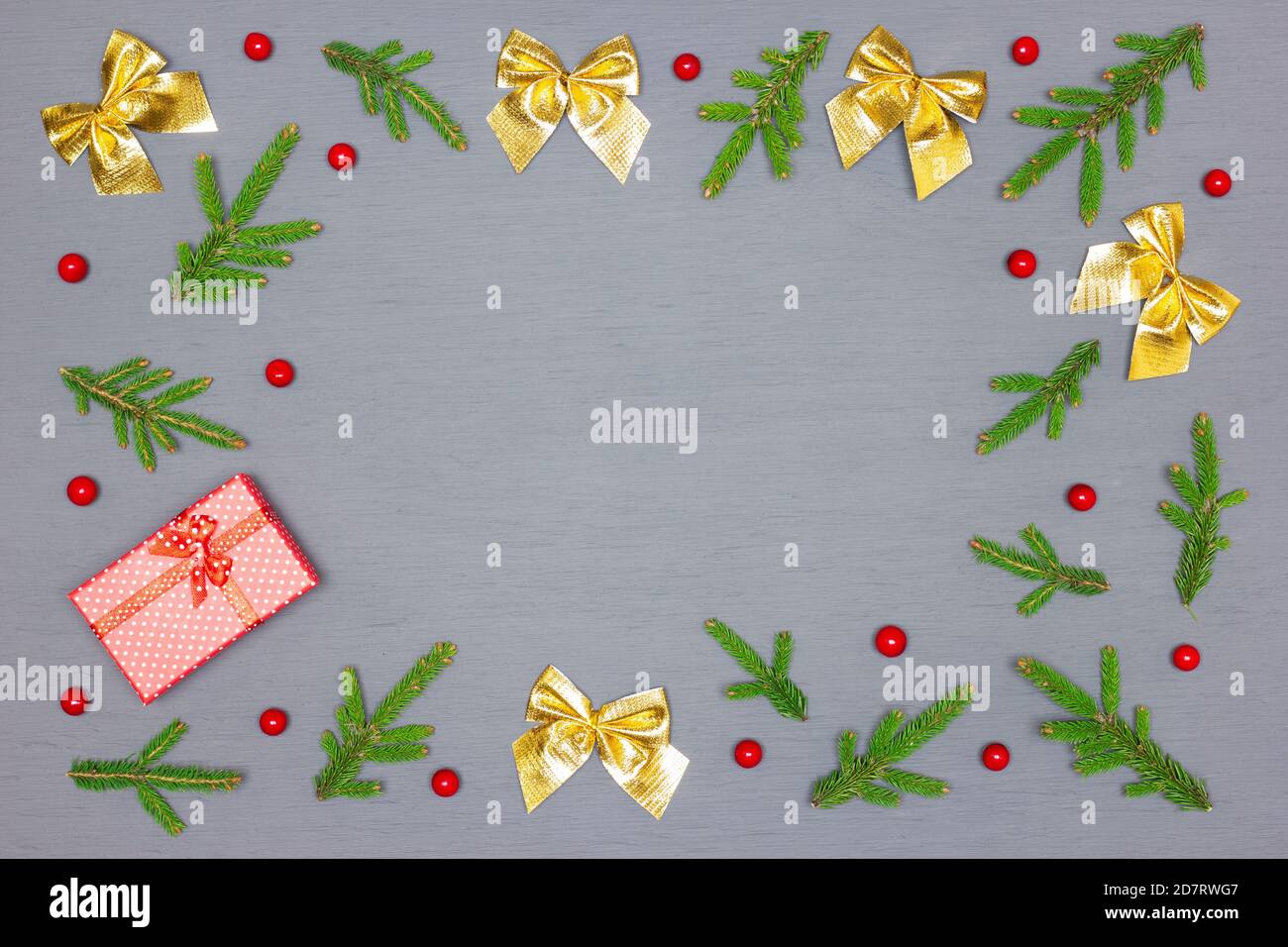 Cadre de branches d'arbre de Noël vertes et décorations de Noël avec boîte cadeau rouge sur bois peint gris. Vue de dessus, plan d'appartement. Espace vide pour le texte Banque D'Images