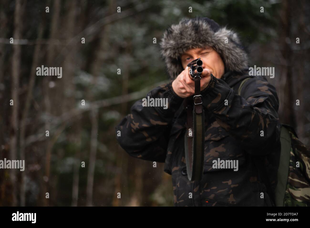 Chasseur visant un fusil de chasse dans une forêt d'hiver Banque D'Images