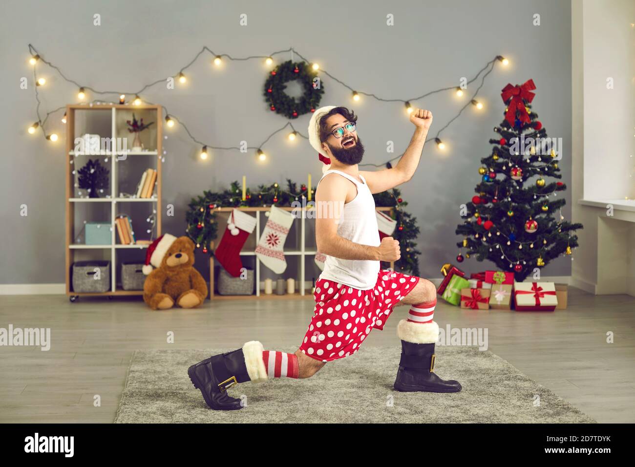 L'homme à l'image d'un drôle de comique Santa Claus danse dans une salle avec des décorations de Noël. Banque D'Images